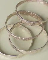 Esclava rígida de diseño artesanal con textura irregular y acabado metálico, ideal para uso diario.