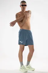 Short de baño azul con cintura elástica y cordón ajustable. Presenta bordados de sirenas en las piernas, bolsillos laterales y bolsillo trasero con cierre.