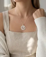 Collar con cadena fina de plata y dije circular de plata 925 con nácar calado en forma de niño.