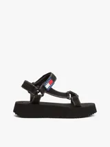 Sandalias de plataforma negras con suela dentada gruesa. Presentan tiras de tejido trenzado ajustables con velcro y un parche tonal con el logo de Tommy Jeans.
