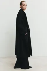 Abrigo largo de corte oversize con cuello de solapa, manga larga y cierre frontal cruzado con botones. Cuenta con bolsillos delanteros.