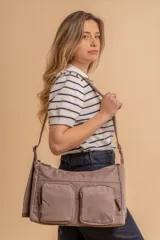 Bandolera de tafeta impermeable color beige, con dos bolsillos frontales con cierre y correa regulable. Diseño práctico y liviano ideal para uso diario.