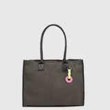 Bolso tipo tote de gamuza en color gris oscuro, con asas largas de cuero sintético negro. Incluye un charm decorativo con cordón amarillo neón y una pieza circular rosada con logo grabado.