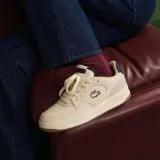 Championes Lacoste modelo L001 Set, de diseño urbano en color blanco con detalles en azul marino y rojo en el talón y la lengüeta. Presenta el logo del cocodrilo bordado en el lateral y suela de goma color caramelo.