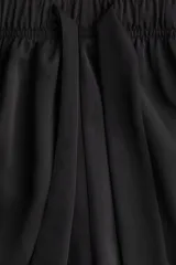 Short negro de sarga con cintura elastizada y cordón para ajustar. De corte holgado y tiro alto, con bolsillos laterales.