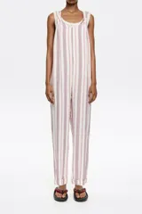 Mono largo de corte recto confeccionado en lino, con estampado de rayas verticales en tonos rojo y azul sobre fondo crudo. Presenta escote redondeado, tirantes con detalle de fruncido y espalda estilo nadadora.