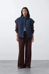 Chaleco acolchado de nylon con diseño capitoneado, cuello alto y cierre frontal con botones a presión. Presenta un calce amplio y versátil.