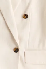 Blazer de doble botonadura confeccionado en sarga de mezcla de viscosa, con solapas de muesca, cierre frontal de botones, pinzas moldeadoras en la cintura y bolsillos delanteros con solapa.