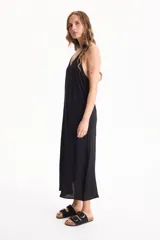 Vestido largo negro de corte holgado, con escote en V y tirantes finos tipo halter.