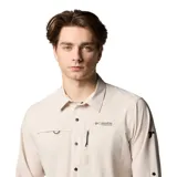 Camisa de manga larga Columbia Titanium, color beige, diseñada para actividades al aire libre. Presenta cierre frontal con botones a presión, bolsillo con cremallera en el pecho, anilla en D y ventilación en la espalda. Confeccionada con tecnología Omni-Shade UPF 50 y Omni-Wick para mayor protección y secado rápido.
