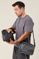 Bandolera negra de tela impermeable con correa regulable.