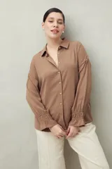 Camisa negra de manga larga con cuello clásico y botones frontales. El tejido presenta una textura arrugada o plisada, y los puños tienen un frunce elástico.