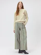 Sweater de punto color beige con cuello alto, detalles de paneles verticales texturizados y monograma bordado en el pecho.