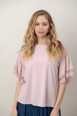 Remera de algodón color blanco, con cuello redondo y mangas cortas holgadas que presentan detalles de encaje broderie.