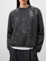Jersey de punto cardado con textura suave y diseño jacquard sutil. Presenta cuello redondo, manga larga y un corte holgado con terminación redondeada.