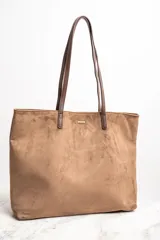 Bolso tipo tote de gran tamaño en color camel, confeccionado en cuero vegano con acabado efecto gamuza. Presenta doble asa larga para llevar al hombro y una placa metálica pequeña con el logo de la marca en el frente.