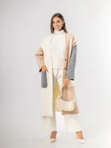 Sacón tipo tapado de corte largo, confeccionado en tejido de punto con diseño color block en tonos gris, negro y blanco. Presenta cierre frontal con botones, bolsillos laterales de parche y aberturas en los costados.