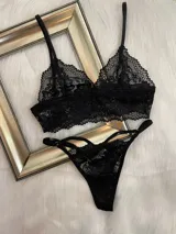 Conjunto de lencería compuesto por un top bralette de encaje con breteles regulables y una tanga colaless regulable con detalles de tiras.