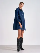 Vestido camisero de denim azul oscuro, marca Elan. Tiene cuello con solapa, abertura central con botones metálicos dorados, bolsillos laterales, mangas largas con puño elastizado, largo mini y calce holgado.