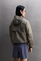 Chaqueta cortavientos de tejido técnico con estructura ripstop, cuello subido con capucha, cierre frontal de cremallera, bolsillos laterales ocultos y zonas perforadas para mayor transpirabilidad.