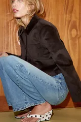 Jeans de tiro alto, color gris oscuro lavado, con pierna ancha extra larga (full length) y diseño de cintura cruzada asimétrica con cierre frontal de cremallera y botones metálicos.