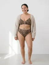 Conjunto de ropa interior compuesto por un corpiño triangular y una bombacha de tiro alto, ambos con estampado animal print y terminaciones en color beige.