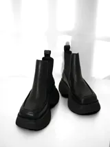 Bota Chelsea de cuero negro con elásticos laterales, tira trasera y suela track.