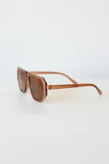 Lentes de sol con armazón de policarbonato en tono caramelo translúcido, diseño de estilo aviador con marco geométrico y protección UV400.
