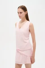 Musculosa de viscosa color rosado, con diseño broderie, breteles anchos, cuello en V y corte holgado.