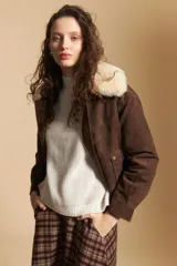 Campera de gamuza color marrón con cuello de corderito sintético en color crema. Presenta cierre frontal, bolsillos laterales con broches metálicos y puños rectos.