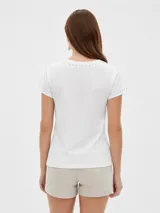 Remera negra de manga corta, con cuello redondo y ajuste al cuerpo. Cuenta con un gran estampado floral en tono gris en el frente y detalle de tachas plateadas alrededor del cuello y en los puños.
