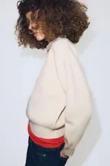 Jersey de punto con cuello tipo polo, manga larga con puños y cierre frontal con botones. Presenta un bolsillo de plastrón en el pecho y diseño de corte holgado.