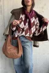Sweater de tejido de punto con diseño de rombos en tonos chocolate, blanco y detalles en bordó. Presenta cuello redondo, mangas largas y terminaciones acanaladas en puños y ruedo.