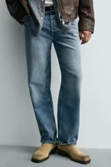 Pantalón de jean con corte recto desde la cadera hasta el tobillo, de tiro medio y ajuste holgado. Presenta diseño de cinco bolsillos, cierre frontal con cremallera y botón, y acabado con efecto lavado.