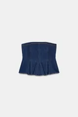 Top tipo corset o peplum de denim azul oscuro, sin tirantes (strapless) y con escote recto. Presenta costuras verticales marcadas y un ruedo con pliegues que le dan volumen en la parte inferior.