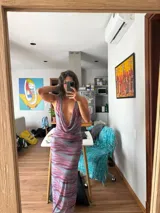 Vestido largo de silueta ajustada, con estampado abstracto en tonos azules, morados y naranjas. Presenta un escote drapeado profundo y tirantes finos.