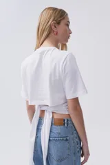 Remera blanca de algodón con cuello redondo y nudo ajustable en la espalda o el frente.