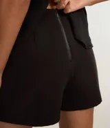 Short pollera negro de bengalina con traspaso delantero abotonado y cierre trasero con cremallera.