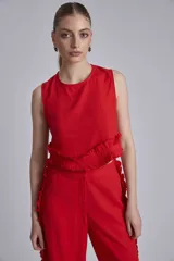 Conjunto de dos piezas color rojo, compuesto por un top sin mangas con detalle de volado fruncido en el bajo y un pantalón ancho de tiro alto con volados largos a lo largo de las costuras laterales exteriores.