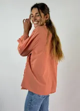 Blusa color beige con cuello mao, mangas 3/4 con puños elásticos y detalle de diseño geométrico texturizado en el frente.