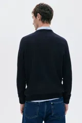 Buzo negro de punto fino con cuello redondo y remates acanalados en cuello, puños y bajo. Presenta un corte estándar para una silueta clásica y cómoda.