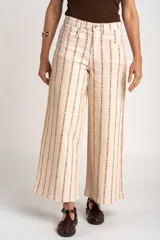 Pantalón jean wide leg de tiro alto, color beige con estampado vertical de líneas y flores marrones, de corte holgado y diseño de cinco bolsillos.