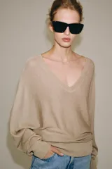 Jersey de punto metalizado color beige, con escote en V y manga larga.