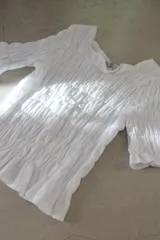 Remera blanca de algodón con diseño fruncido en todo el cuerpo y mangas cortas con terminación de volado.