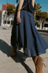 Falda midi azul oscuro, de tiro alto, con corte evasé y textura arrugada o plisada. Presenta un forro interior y cierre lateral oculto.