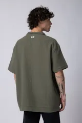 Chomba de manga corta con cuello polo, confeccionada en tejido de punto acanalado de textura pesada. Presenta un calce relajado y cuenta con una pequeña etiqueta distintiva en el ruedo.