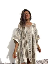 Poncho de tejido rústico color crudo con estampado geométrico en marrón y flecos.