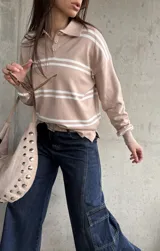 Sweater de punto con rayas horizontales blancas y base en tono beige y rosado, cuello polo con botones y mangas largas.