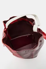 Bolso de hombro formato maxi de piel, en combinación de colores rojo y bordó. Cuenta con detalle de pespuntes, bolsillo interior con cremallera extraíble y cierre mediante fruncido con asas finas de hombro.