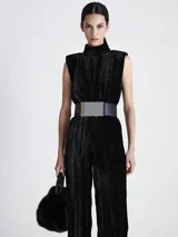 Mono largo de terciopelo negro con cuello alto, sin mangas, corte holgado y cinturón ancho plateado.